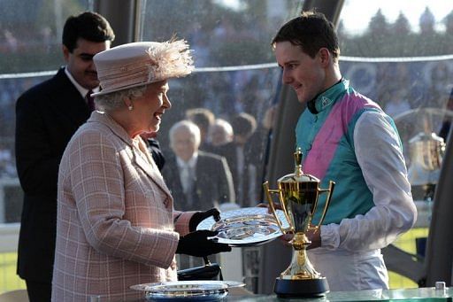 Queen Elizabeth II presents a trophy to Tom Queally, rider of Frankel, at The Queen Elizabeth II Stakes in 2011